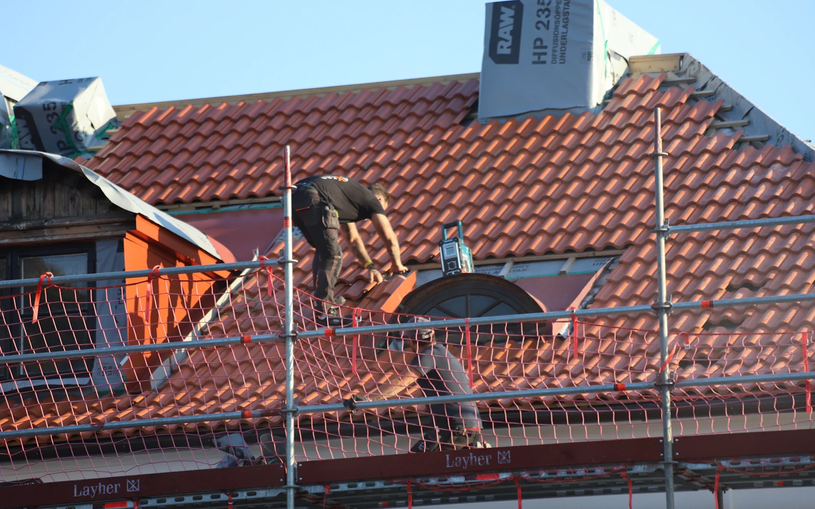 Profesional trabajando con protección colectiva sobre una cubierta inclinada de teja